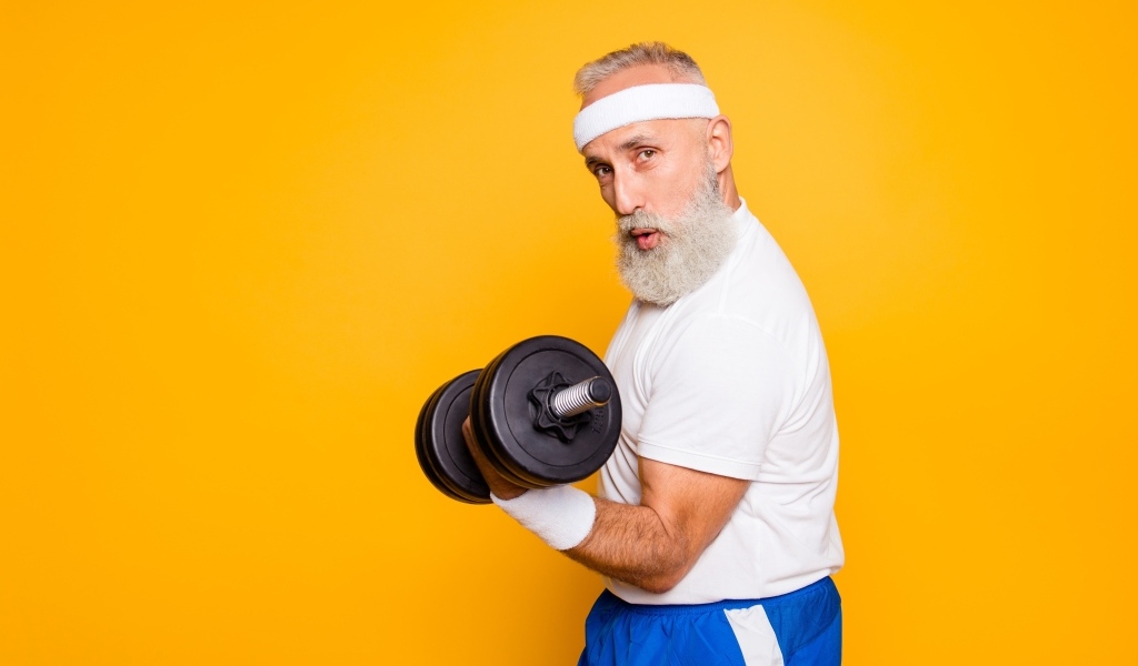 Спортивный мужчина с гантелей в руке на желтом фоне