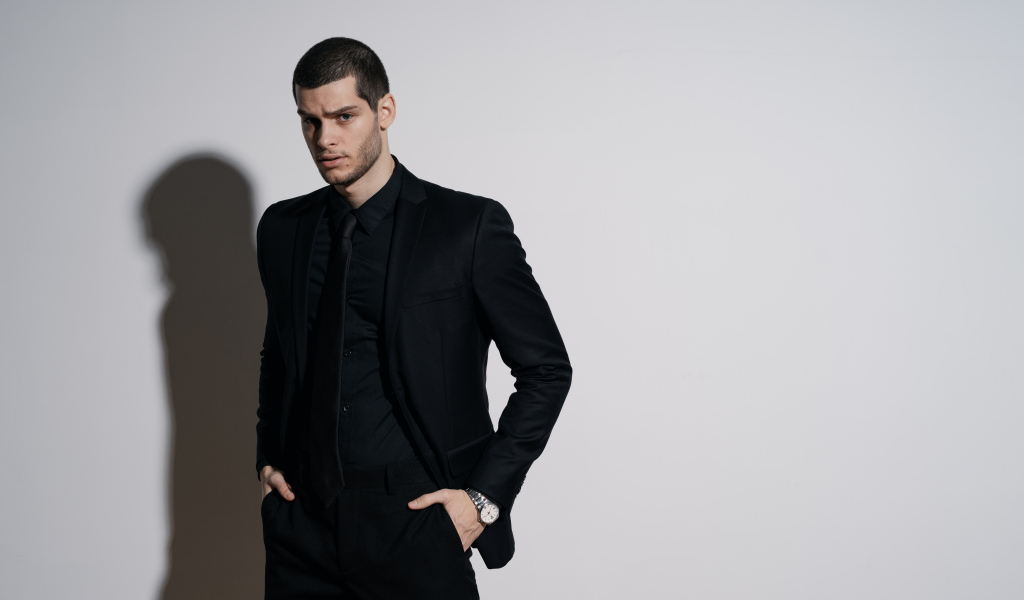 Красивый деловой мужчина стоит у серой стены