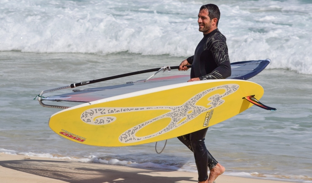 Мужчина серфер с доской на пляже