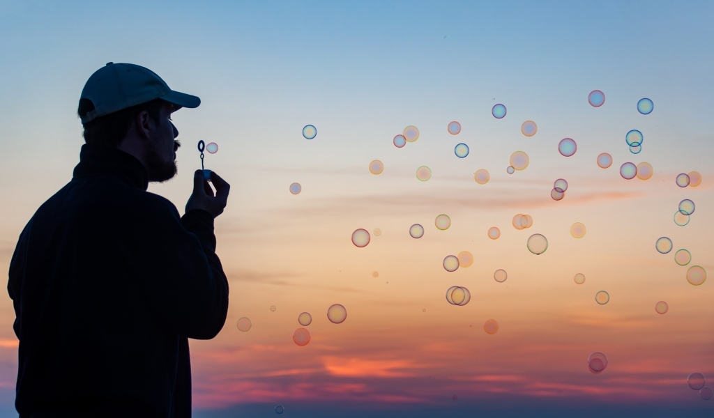 Мужчина пускает мыльные пузыри на закате