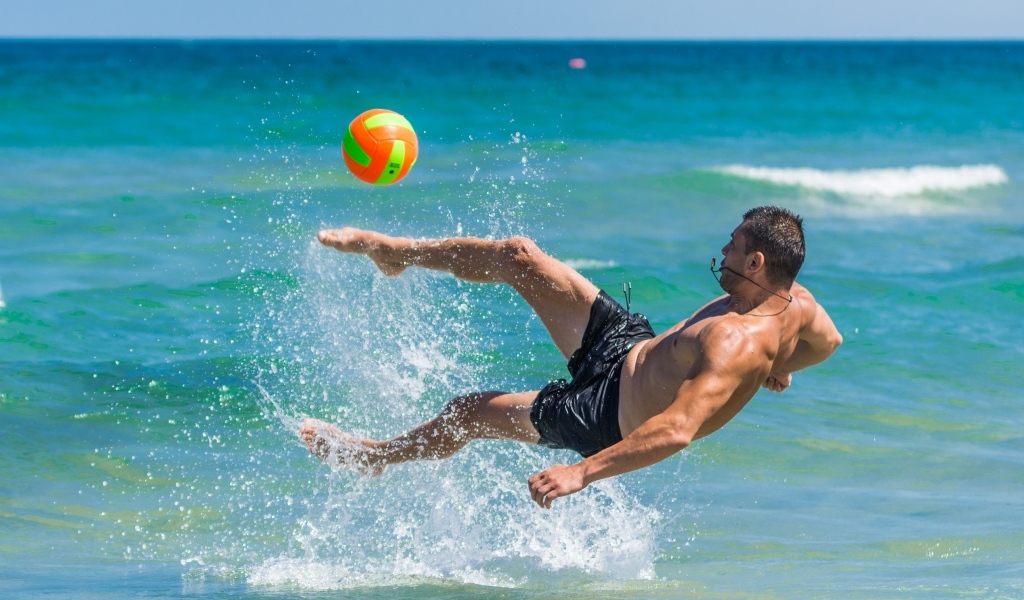 Мужчина играет в пляжный футбол