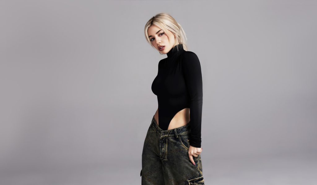 Милая блондинка певица  Эйва Макс на сером фоне