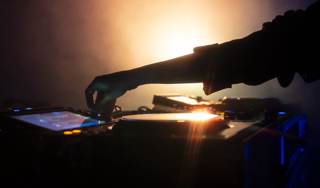 Рука диджея настраивает музыкальный пульт 