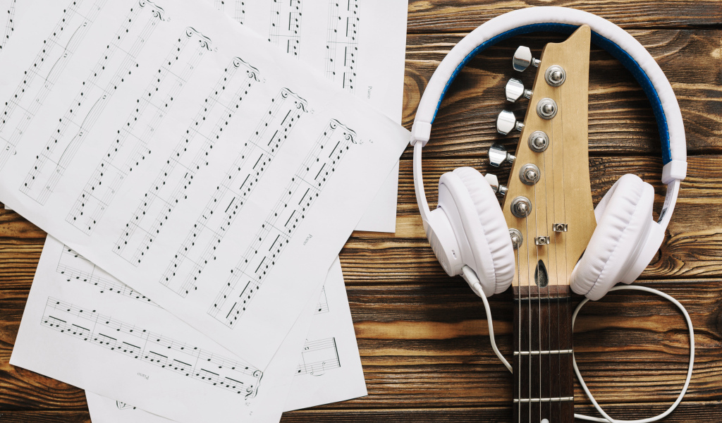 Ноты, наушники и гитара на столе