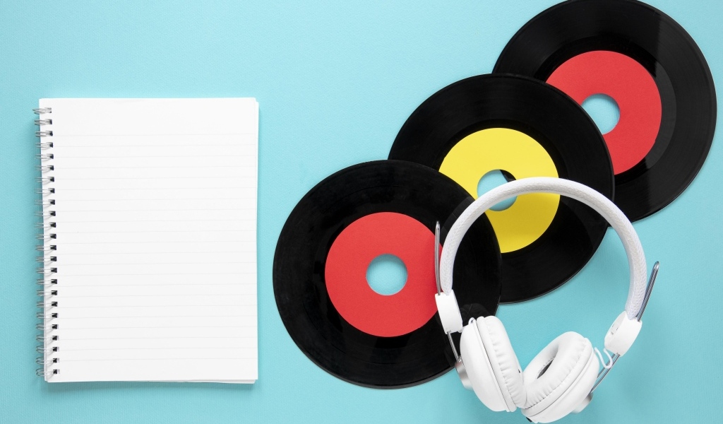 Пластинки на голубом фоне с блокнотом и наушниками