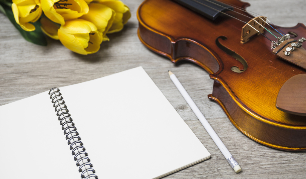 Скрипка, блокнот и желтые тюльпаны на столе