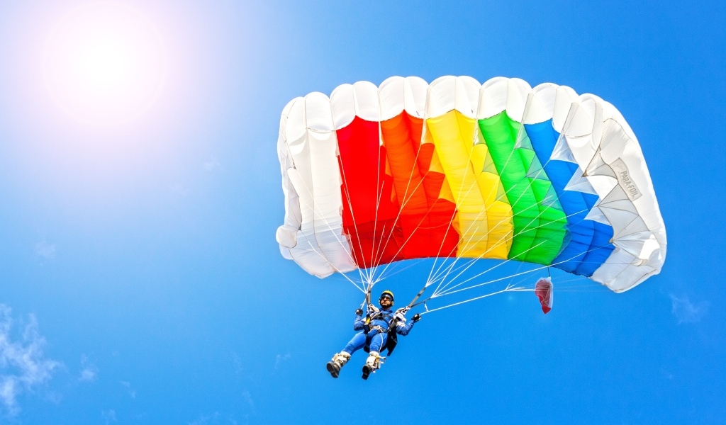 Парашютист в голубом небе в лучах солнца