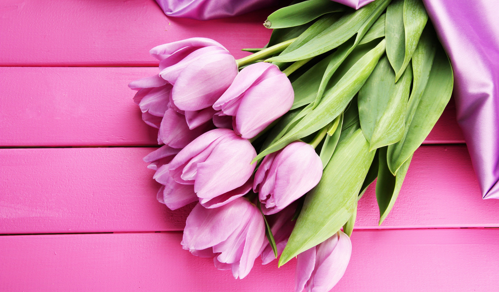 Красивый букет тюльпанов с лентой на розовом столе