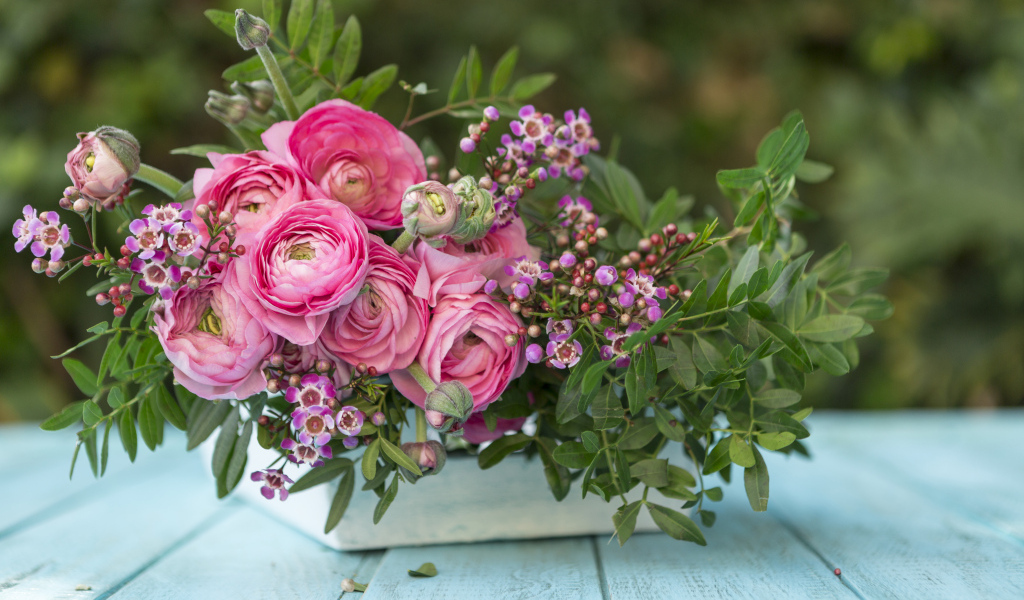 Букет розовых цветов лютика в ящике на голубом столе