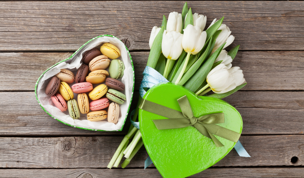 Букет белых тюльпанов на столе с коробкой печенья макарун