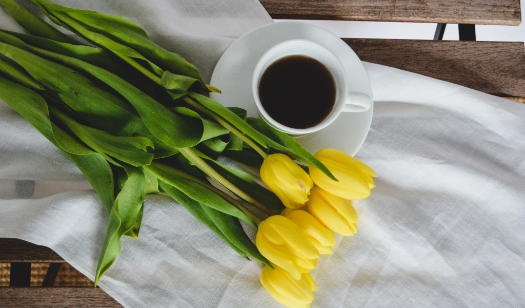 Букет желтых тюльпанов с чашкой кофе на лавке