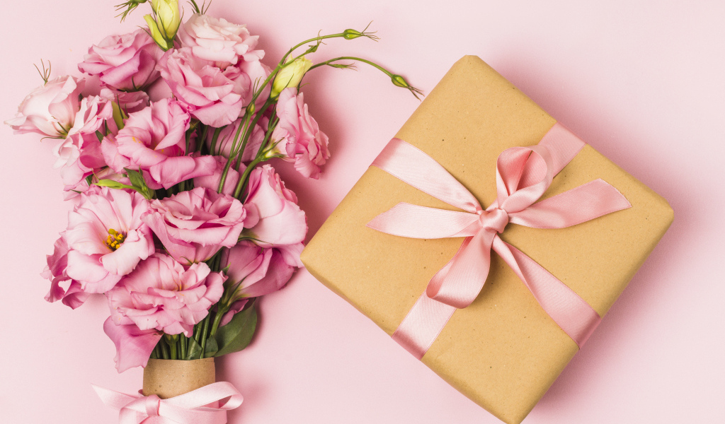 Большой букет эустомы с подарком на розовом фоне