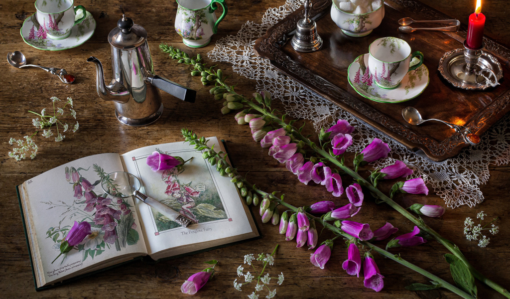 Розовые цветы на столе с книгой и чаем