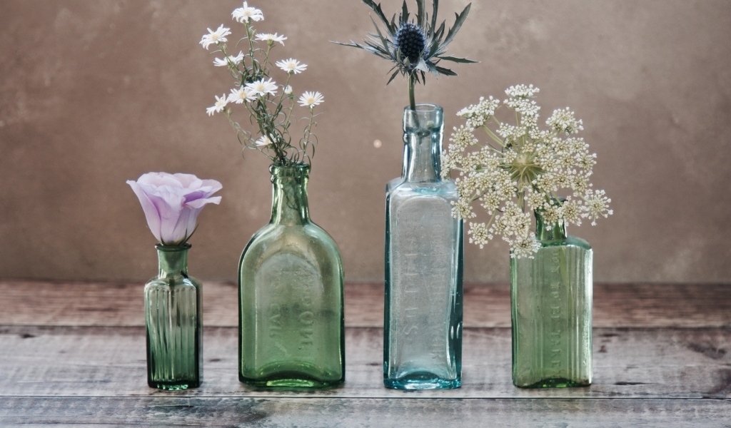 Полевые цветы в стеклянных банках на деревянном столе