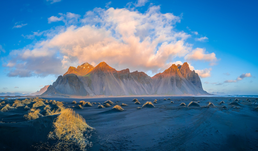 Облако в голубом небе над покрытой солнцем горой