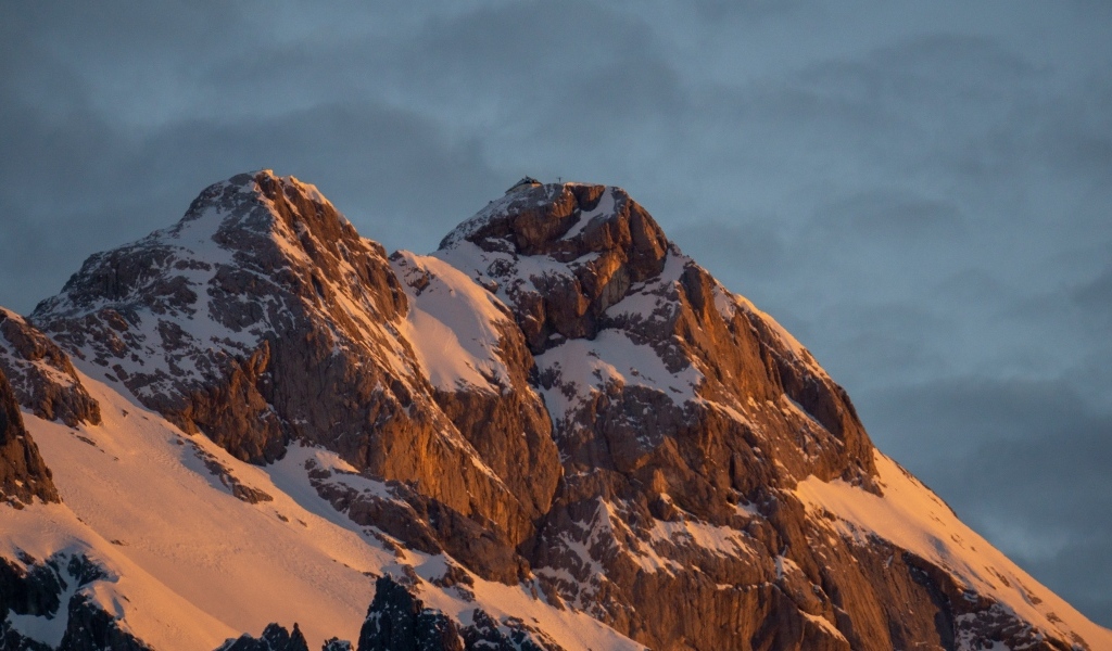 Высокие опасные заснеженные горы под грозовым небом
