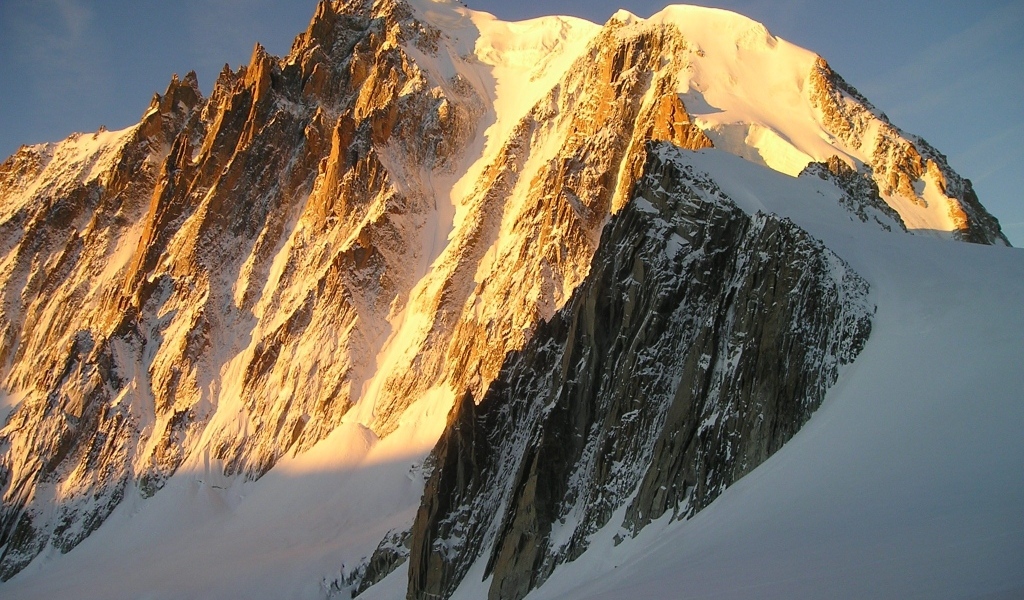 Заснеженная высокая гора в лучах яркого солнца
