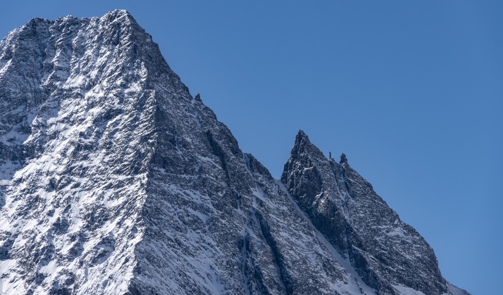 Крутая вершина горы в снегу на фоне голубого неба