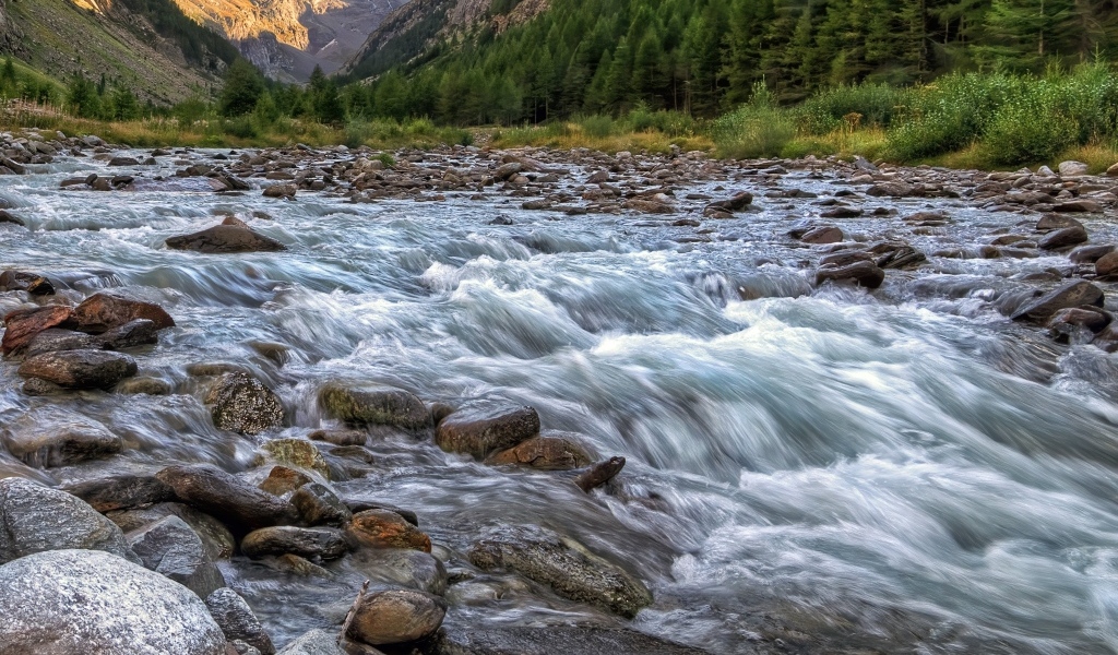 Быстрая холодная река стекает по камням в горах 