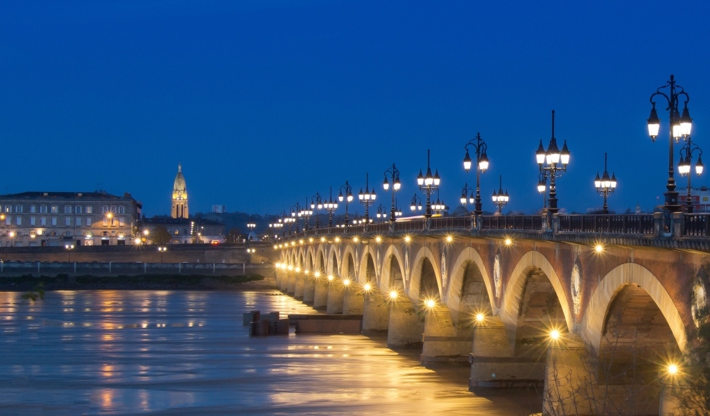 Красивый светящийся мост через реку ночью 