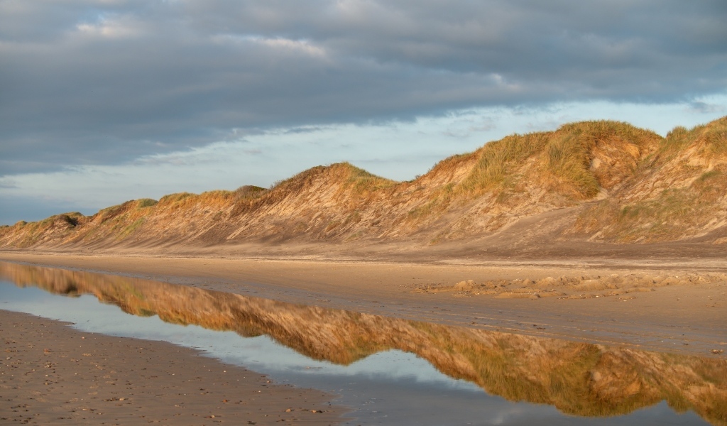 Холты отражаются в реке под грозовым небом