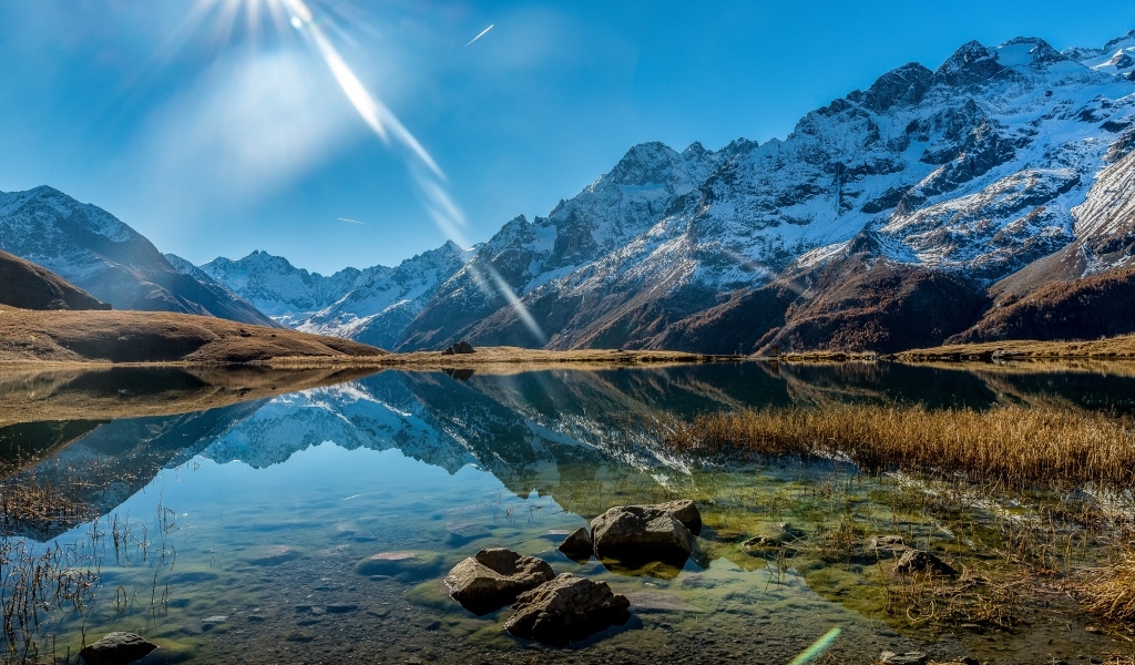 Лучи яркого солнца освещают гору и озеро