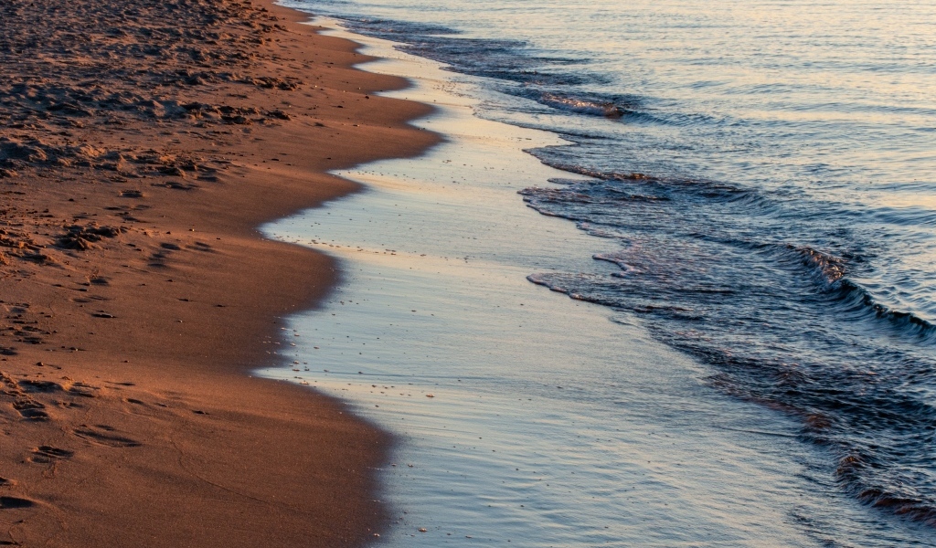 Спокойное море на морском песке на рассвете