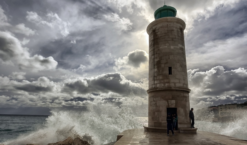 Волны бьются о маяк под красивым небом