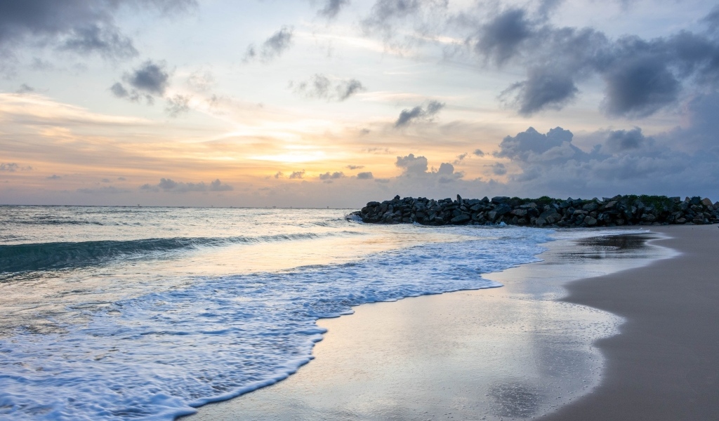 Волны омывают морской песок на рассвете