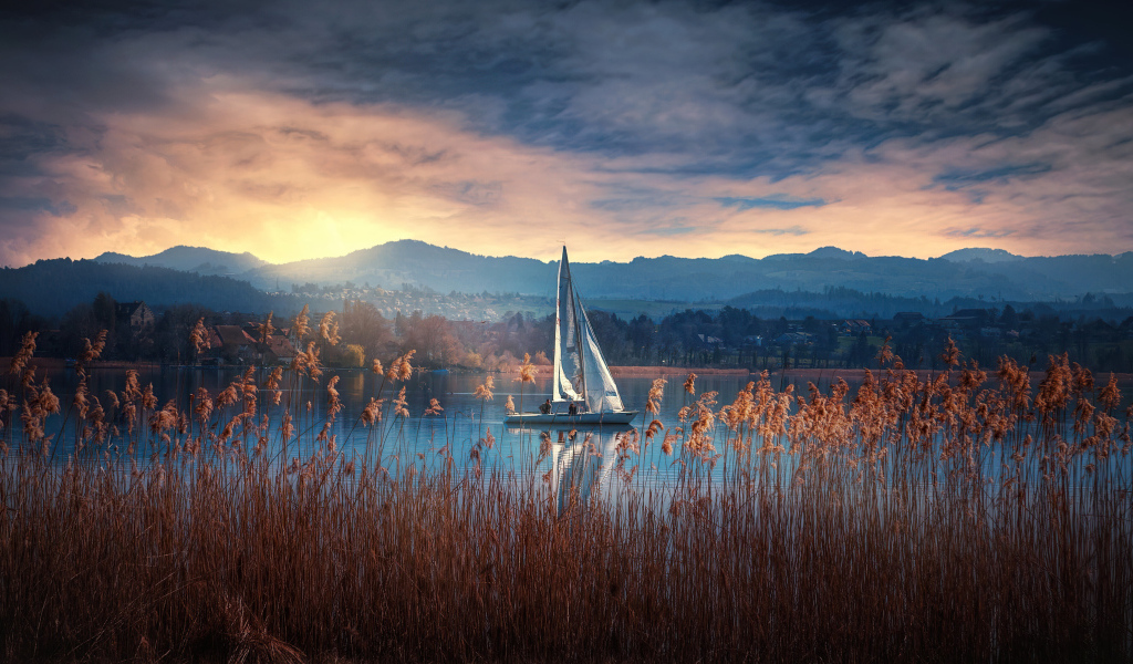 Парусная лодка на озере на закате солнца