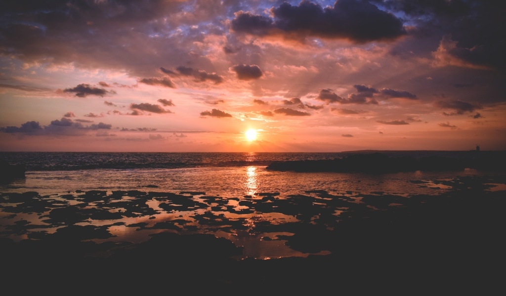 Закат яркого летнего солнца в небе над морем