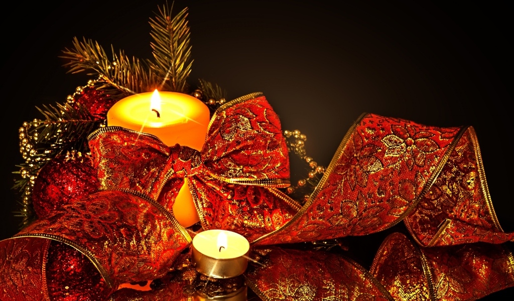 Зажженная свеча с красным бантом на черном фоне на Новый год