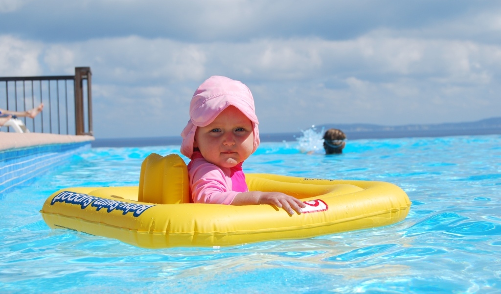 Ребенок со спасательным кругом плавает в бассейне