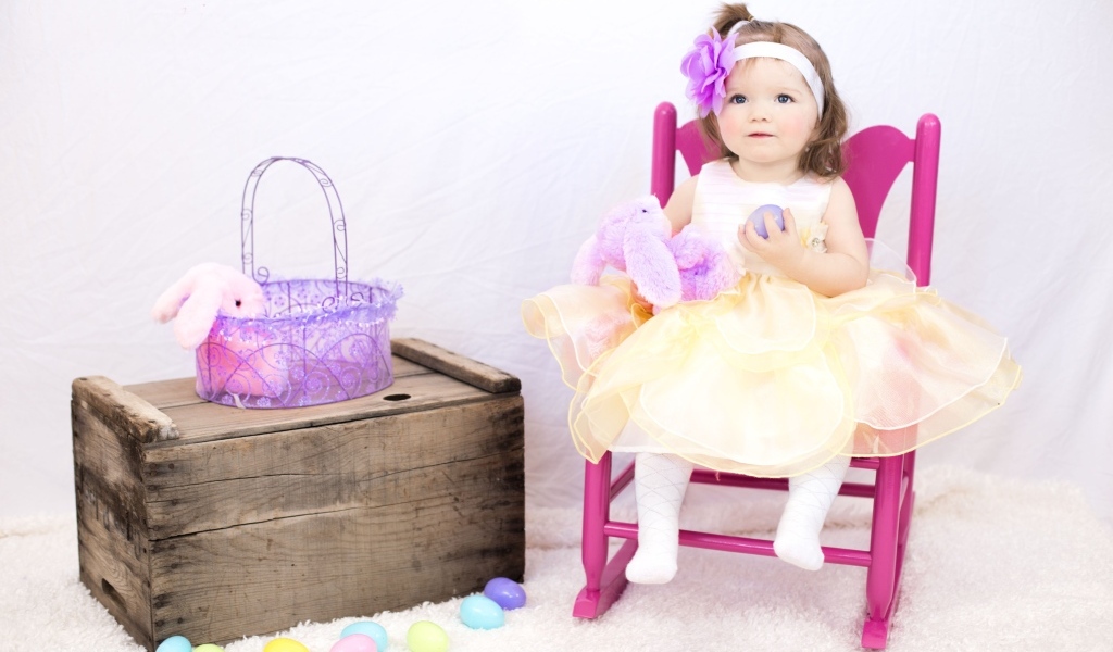 Девочка в красивом платье сидит на стуле 