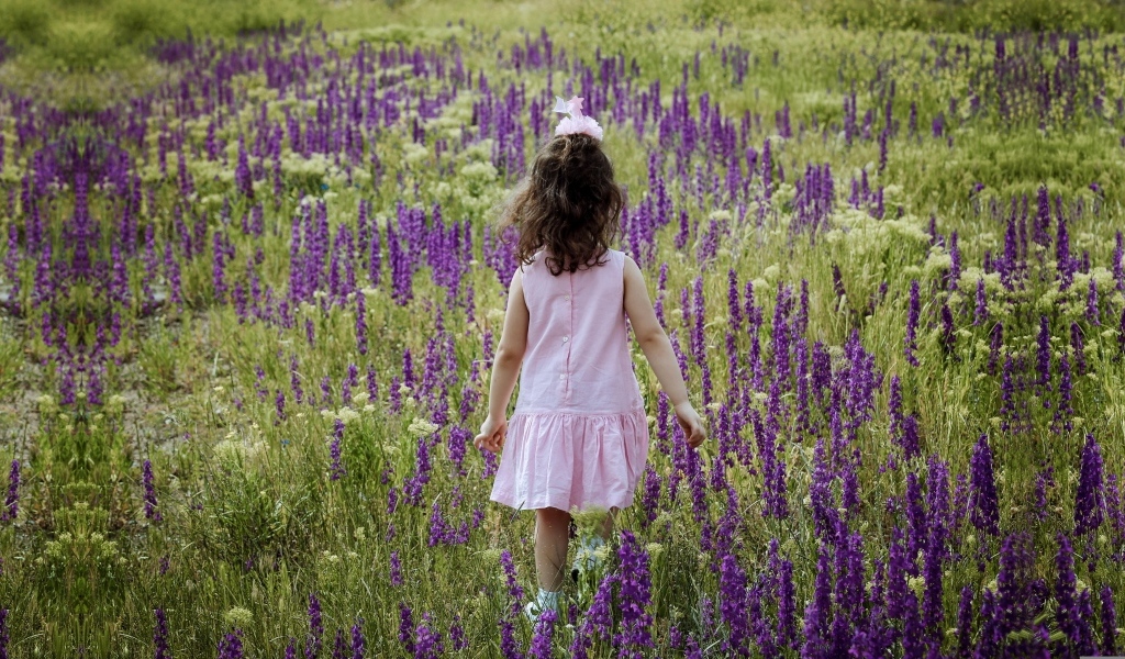 Девочка в розовом платье гуляет по полю с цветами