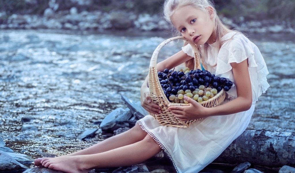 Девочка с корзиной винограда сидит у воды