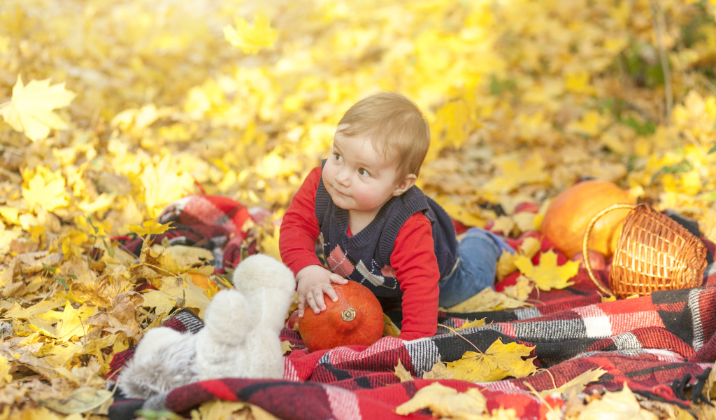 Маленький ребенок лежит на покрывале на земле осенью