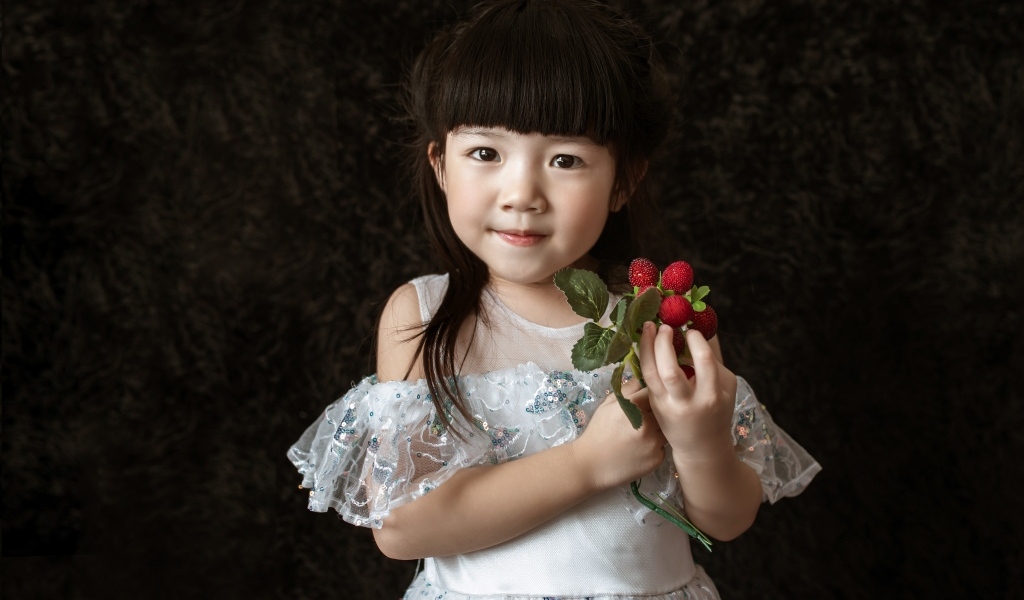 Девочка азиатка в белом платье с ягодами в руке