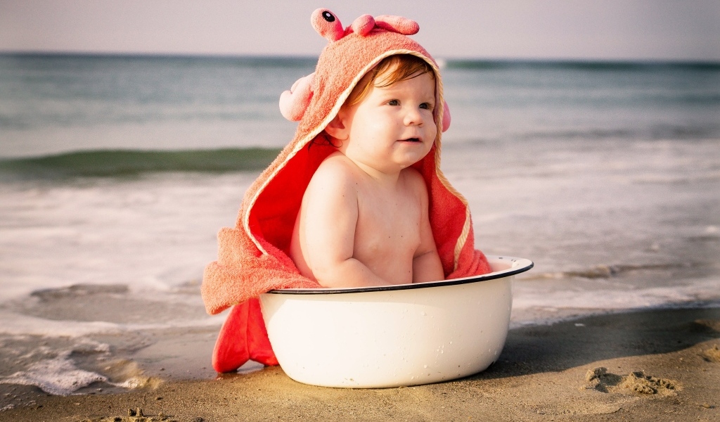 Ребенок в миске на берегу моря