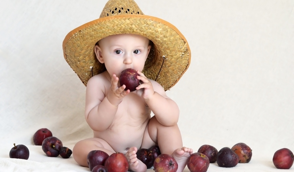 Малыш в шляпе грызет яблоки