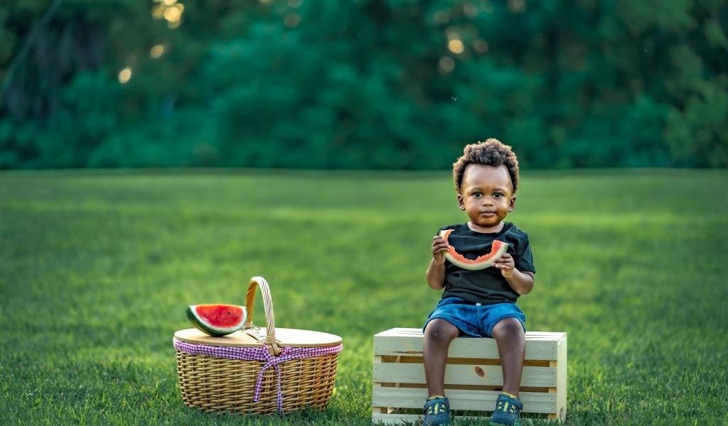 Темнокожий мальчик ест арбуз на природе