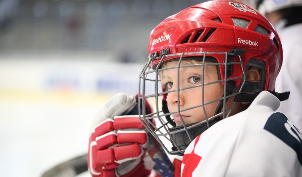 Мальчик в красном шлеме хоккеиста на поле