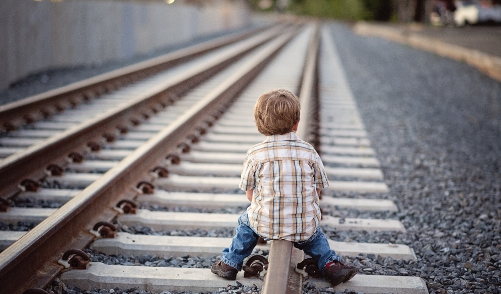 Мальчик сидит на железнодорожных рельсах