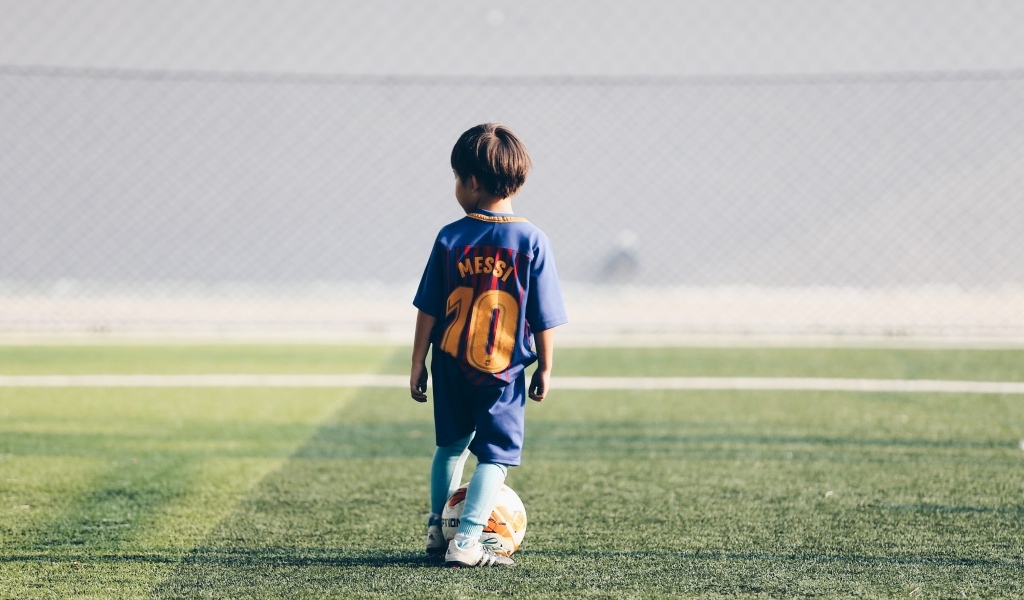 Мальчик футболист с мячом на поле