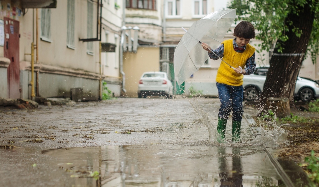 Мальчик с зонтом прыгает по лужам