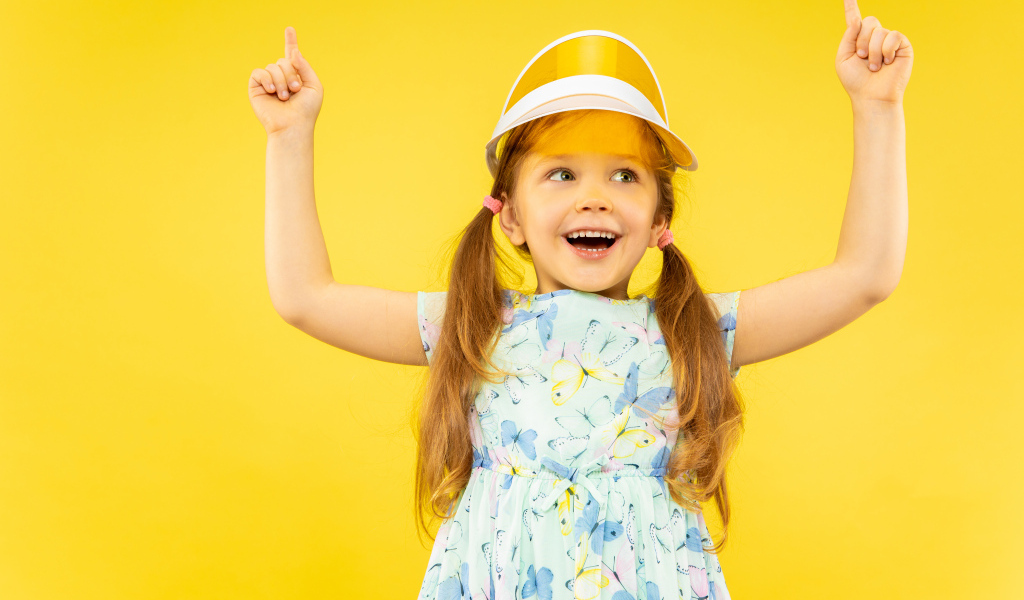 Веселая девочка в платье на желтом фоне