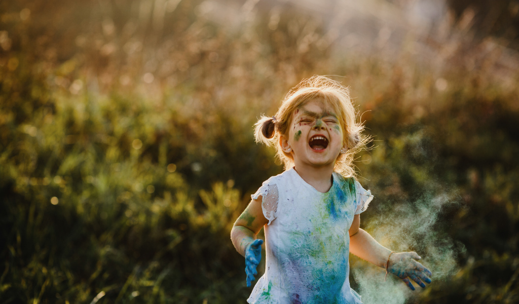 Веселая девочка в краске на улице