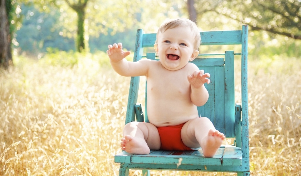 Веселый маленький мальчик в кресле 