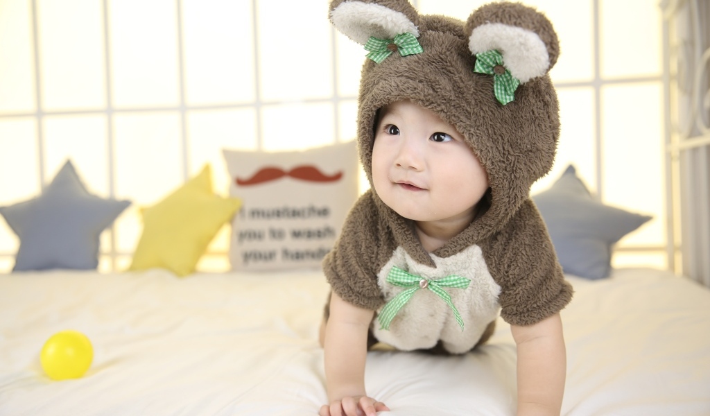 Ребенок в костюме медвежонка на кровати