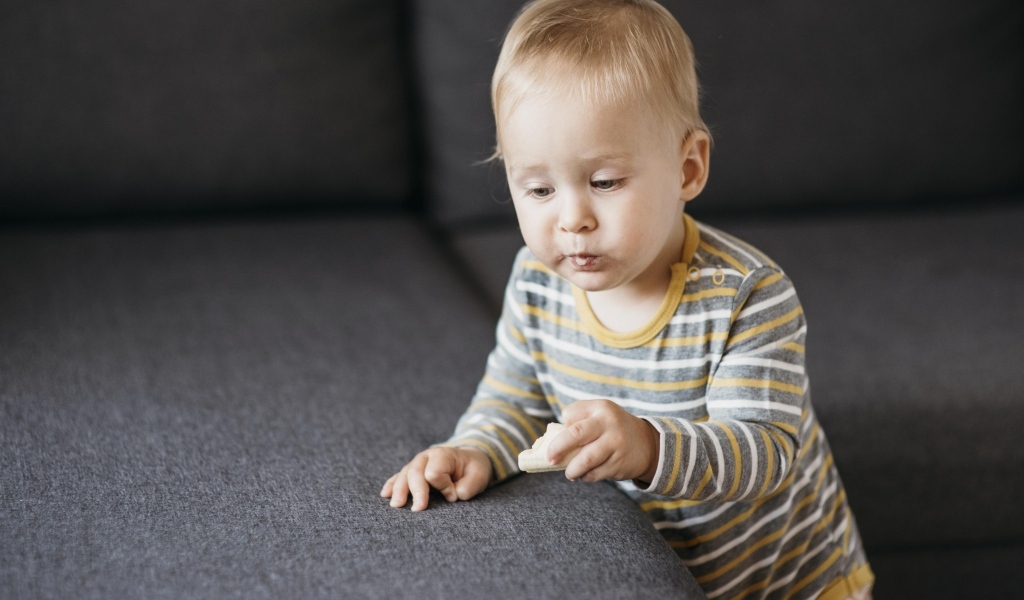Любопытный маленький ребенок у дивана